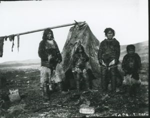 Image: Family standing by tupik. Meat drying on rack