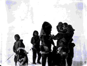 Image of Inuit women, and children holding dog on a lead