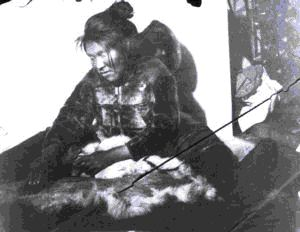 Image: Inuit woman working on furs; baby in hood