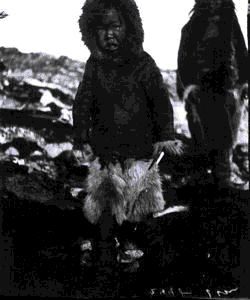 Image: Young Inuit boy in furs holding game of skill