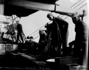 Image: Crewmen working on deck, one using camera