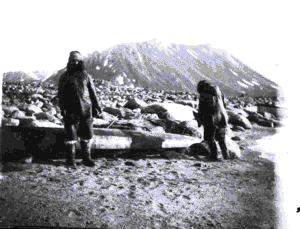 Image of 2 Inuit men by overturned kayak