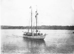 Image of The Bowdoin with many guests aboard. Three men high in rigging