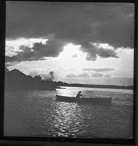 Image of Man Rowing Boat, House Visible on Shore