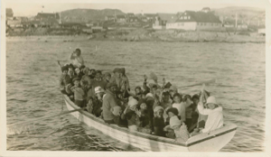 Image: Boatload of villagers waving as they leave the Bowdoin