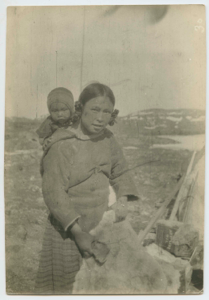 Image of Mother with child on back, handling furs