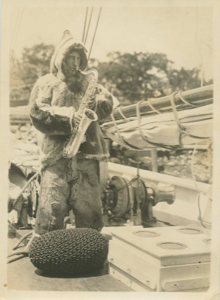 Image of Donald Mix? In furs aboard the Bowdoin, playing a saxophone