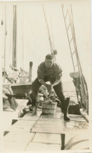 Image of Richard Goddard on deck, standing on crates of supplies