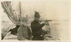Image of Crew man in headnet and Thomas McCue with pistol - on deck