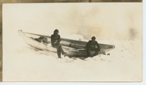 Image of Thomas McCue and Donald Mix sitting on gunwale of dory in ice