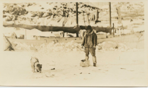 Image of Thomas McCue and dog near iced-in Bowdoin. Fox tails hanging
