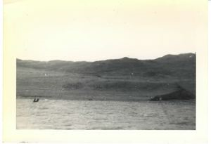 Image: Shoreline. Two men in small boat in distance.