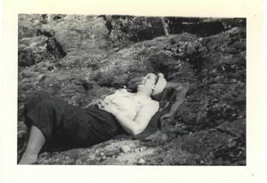 Image of Martha Burt, American Red Cross worker, lying on rocky slope, laughung