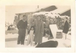 Image of Greenlandic family outside their stone/wood house