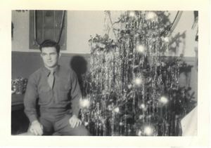 Image of Serviceman sitting by Christmas tree