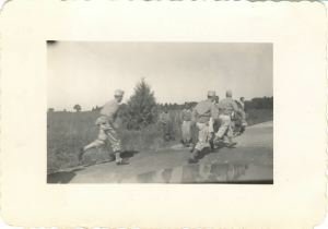 Image of Three soldiers running; children watching
