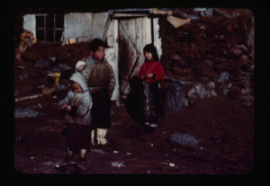 Image of Inuit children by stone house