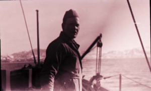 Image of Man standing on vessel - hills beyond