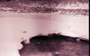 Image of Water flowing under snow-covered ice