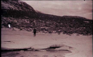 Image of Man standing on snow-covered ice, by water