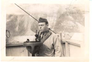 Image of Rutledge with pipe on deck, studying devise (compass?)
