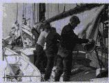 Image of Four crewmen working with sail
