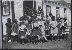 Image of School children by school doorway with Dr. and Mrs. Hettasch and Freida Hettasch