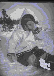 Image of Eskimo [Inuk] girl sitting on snow, hand over face