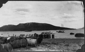 Image of View to water showing supplies on beach and both ships beyond