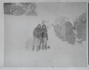 Image: Two Inuit men by rocks  