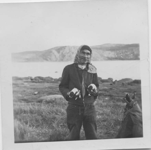 Image of Innu man holding two young pups [Uniam (William) Katshinak]