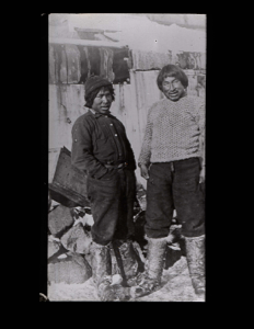 Image of Two Inuit men by frame building