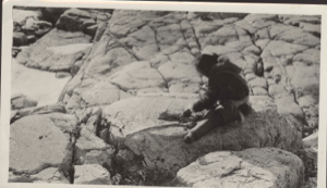 Image of Woman on rock making thread from caribou sinews