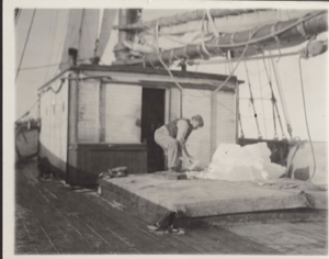 Image of The "Cluett's" cook beside galley door. Chunk of ice on the forehatch