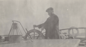 Image of Captain George Comer at the wheel of the "Cluett"