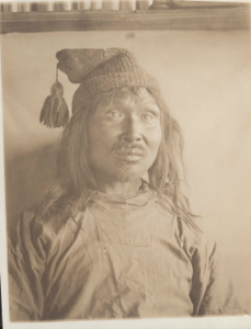 Image: Accomoding-wah [inuit man wearing knit cap with large tassel. Portrait]