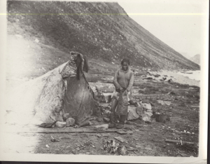 Image of Ah-wee-a-good-loo at Nerky [Inuit woman standing by tupik. Wears short boots, holds legging]