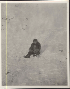 Image: Megipsoo with sled [Inuit girl sitting on small sled]