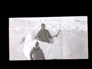 Image of Crewman with snowknife building igloo [iglu]. Inuit girl near
