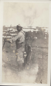 Image: Inuit man with backpack held by head strap; with rifle