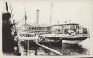 Image of Large ocean liner. Many  sailors aboard, many people on pier