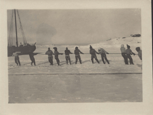 Image of Nine women pulling rope toward moored vessel