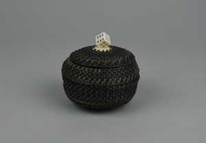 Image of black and white baleen basket with a (gaming) die as finial