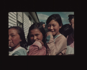 Image: Three smiling school girls. Donald MacMillan in background
