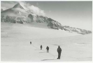 Image: Men trekking on snow near mountain peak