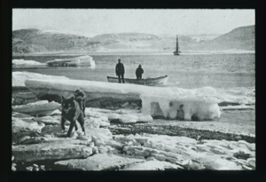 Image of Iceberg remains. Two men with dory by one. Dog on ice in foreground