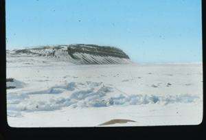 Image: Distant striated cliff. Snow in foreground