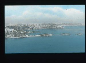 Image: View across water to striated hills, with snow                                 