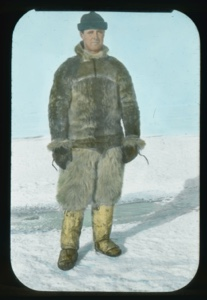 Image: Portrait: Donald MacMillan in seal skin parka, knit cap, standing on snow