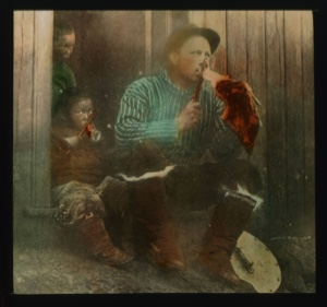 Image: Maurice Tanquary (?) sitting on steps - eating meat Inuit manner....